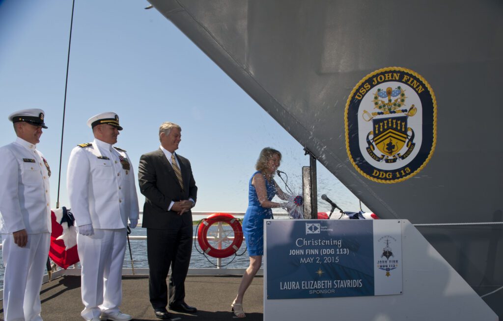 150502-N-OT964-276 PASCAGOULA, Miss. (May 2, 2015) Ship sponsor Laura Stavridis ceremoniously breaks a bottle of champagne on the bow during the christening ceremony for the future guided missile destroyer USS John Finn (DDG 113). The ship is named after the Medal Of Honor Recipient and prior Aviation Ordnanceman Chief John Finn who survived and fought during the attack on Pearl Harbor. (U.S. Navy photo by Mass Communication Specialist 1st Class Martin L. Carey/Released)