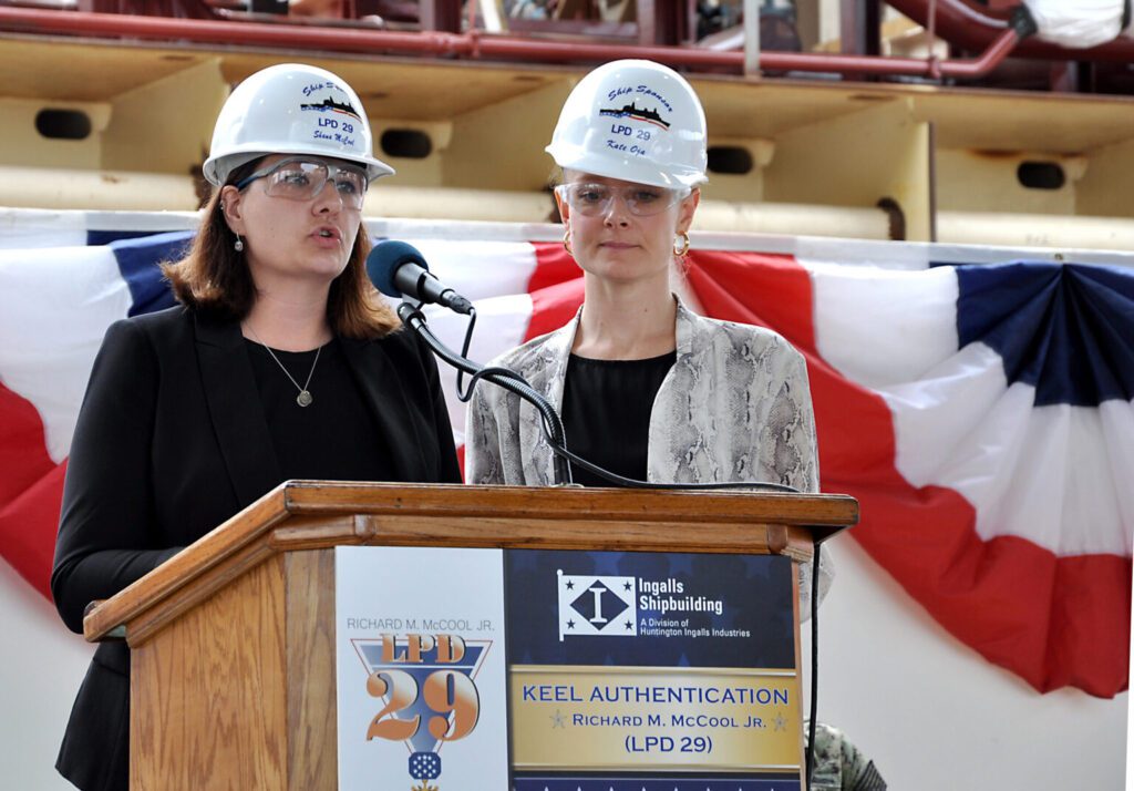 190412-N-BR740-1054: Left, Shana McCool and Kate Oja, ship sponsors of the future USS Richard M. McCool Jr. (LPD 29), speak about their grandfather during the keel authentication ceremony for the ship at Huntington Ingalls Industries Pascagoula shipyard April 12. Then a Navy captain, McCool received the Medal of Honor for his heroic actions in rescuing survivors from a sinking destroyer and for saving his own landing support ship during an enemy attack while injured. (U.S. Navy photo by Samantha Crane/Released)
